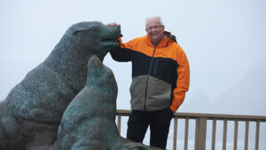 Owner of Sea Lions Caves standing with statue outside.